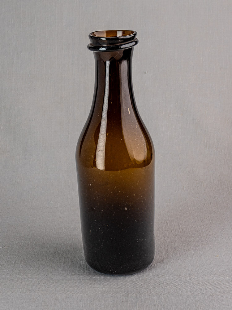 Antique French hand-blown glass truffle jar with narrow neck and flared lip on gray surface.