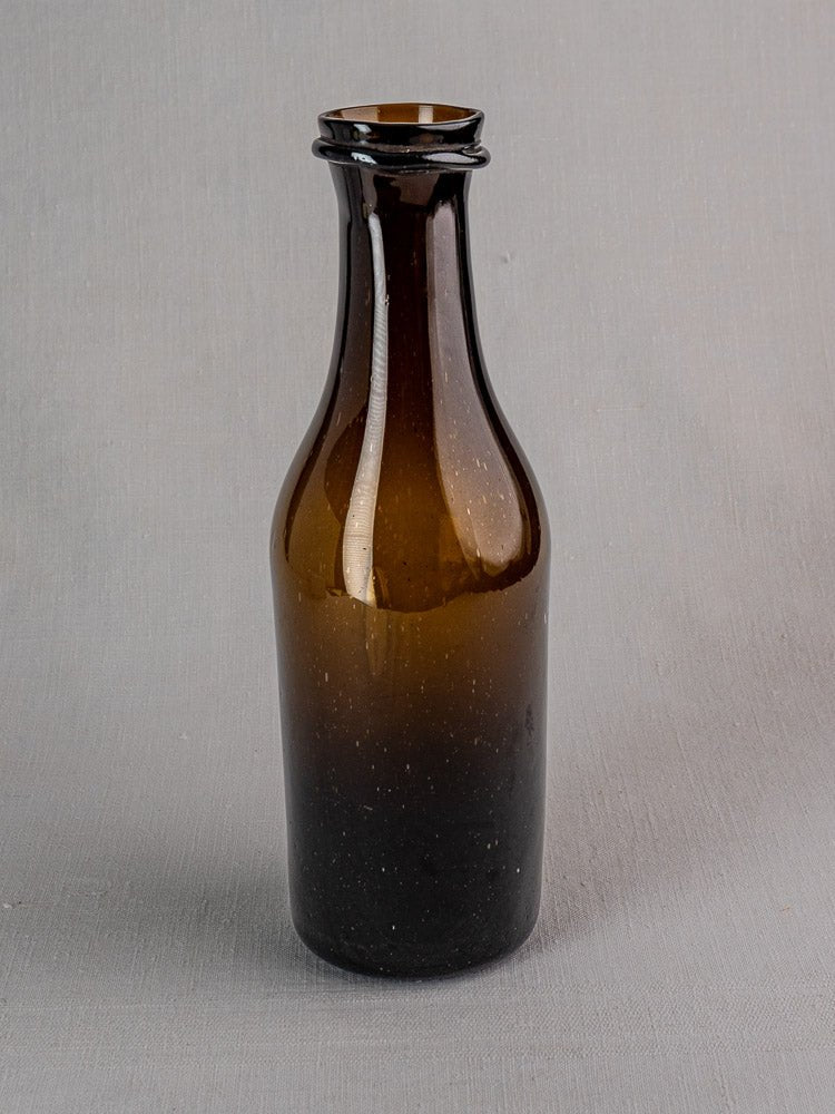 Antique French hand-blown brown glass truffle jar with narrow neck on gray surface.