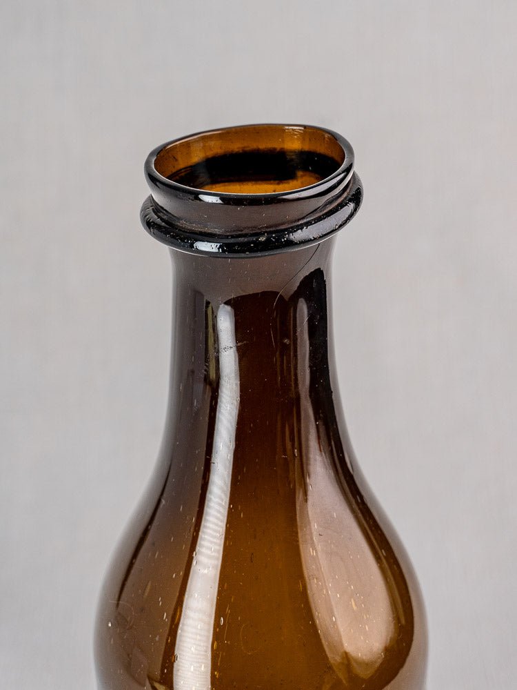 Antique French hand blown glass truffle jar with uneven rim, plain light background.