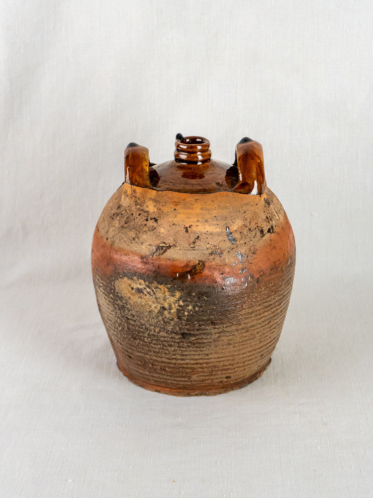 Antique French glazed terracotta jarre à huile with brown glaze, round body, and narrow spout.
