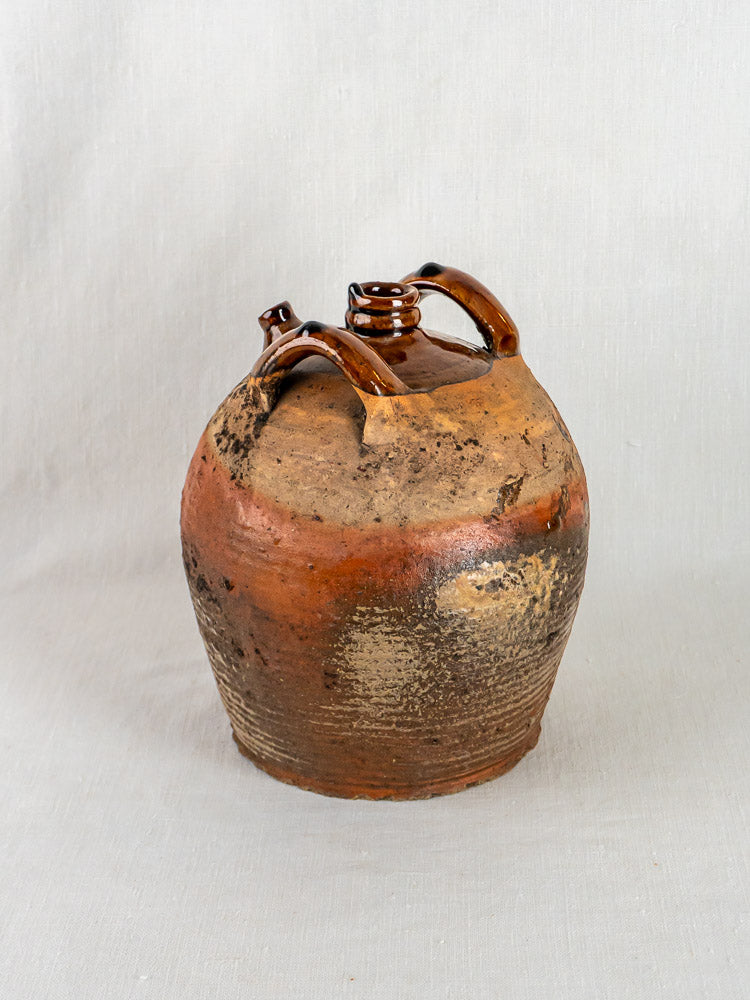 Antique French glazed terracotta oil jar with two handles, rustic brown body, and narrow neck.