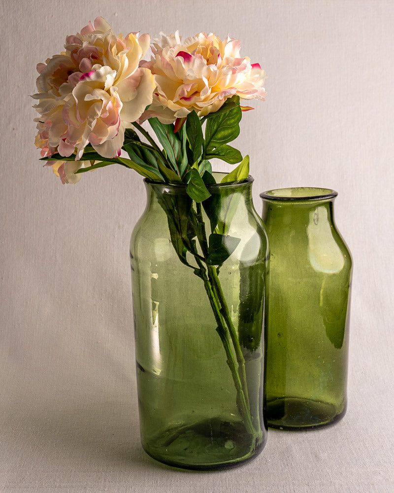 Pair of late 18th-century French green glass cornichon jars, one filled with faux peonies, on light surface.