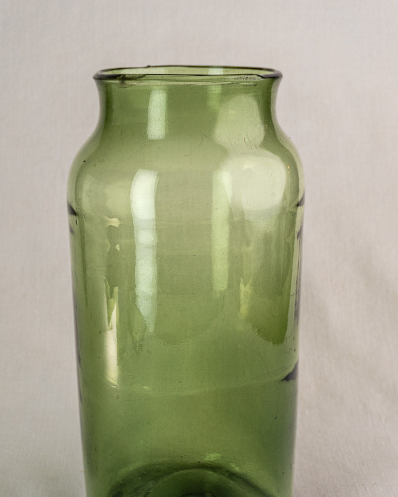 Antique French cornichon jar, translucent hand-blown green glass, late 18th century, flared rim, on plain background.