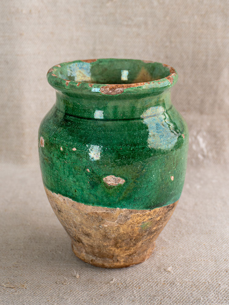 19th-century French confit pot with green-glazed top and unglazed terracotta base, set on neutral fabric.