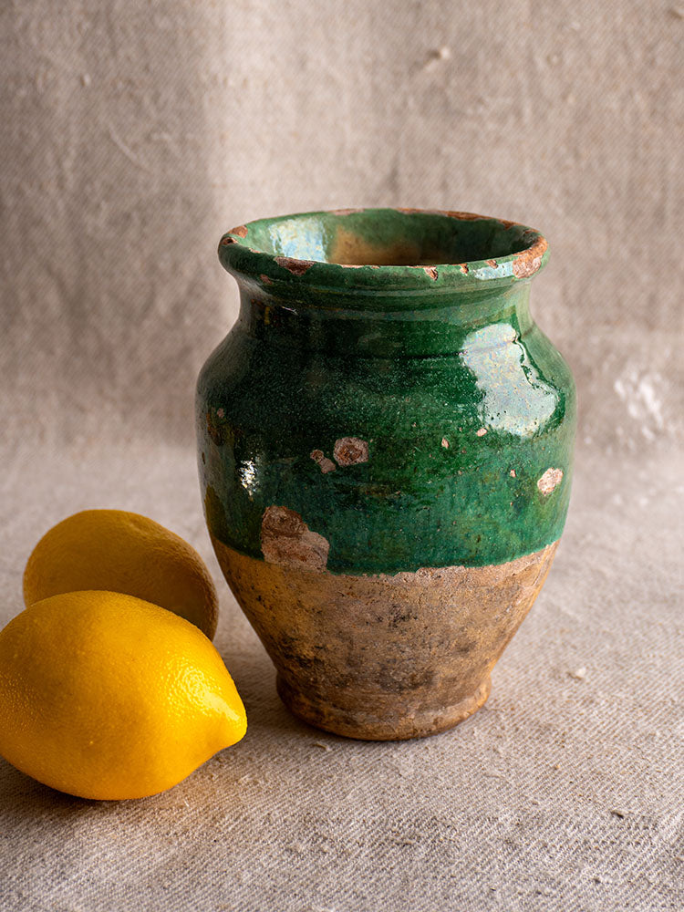 19th-century French confit pot with green-glazed top and unglazed terracotta base, set on neutral fabric.