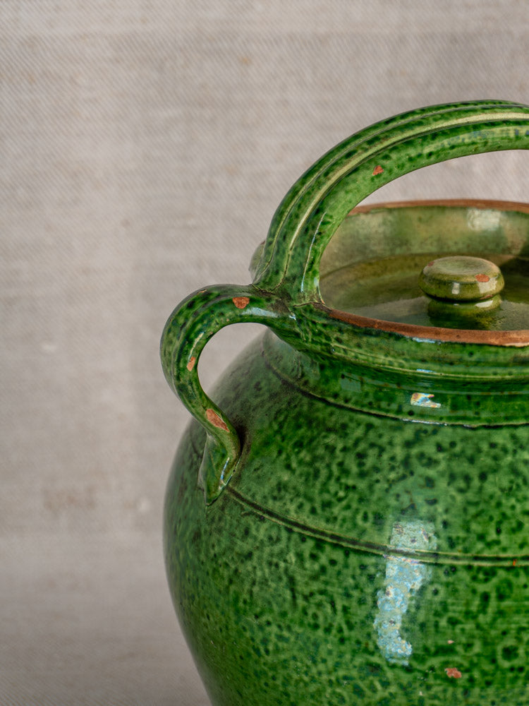 Antique French green glazed cruche orjol from Languedoc with lid, curved handles, worn emerald glaze on neutral fabric.
