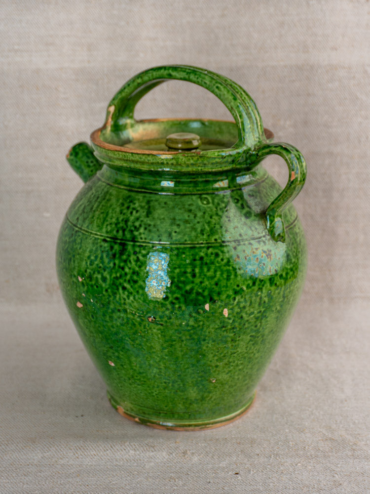 Antique French green glazed cruche orjol water jug with two handles, spout, minor chips; on neutral fabric background.