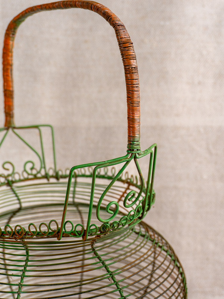 Antique French green wire egg basket with original paint, scroll rim, loops, and brown wire-wrapped handle. Mid-century kitchenware.
