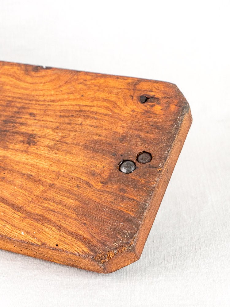 Antique French bread cutter with beveled wooden board, metal rivets, and visible wood grain knot.