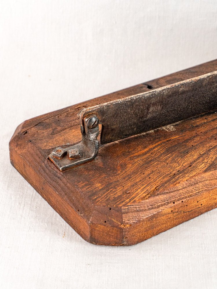 Antique French guillotine bread cutter with wooden base and metal blade on a light surface.