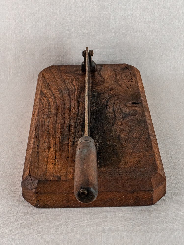 Antique French bread cutter with wooden body, metal guillotine blade, and handle on neutral background.
