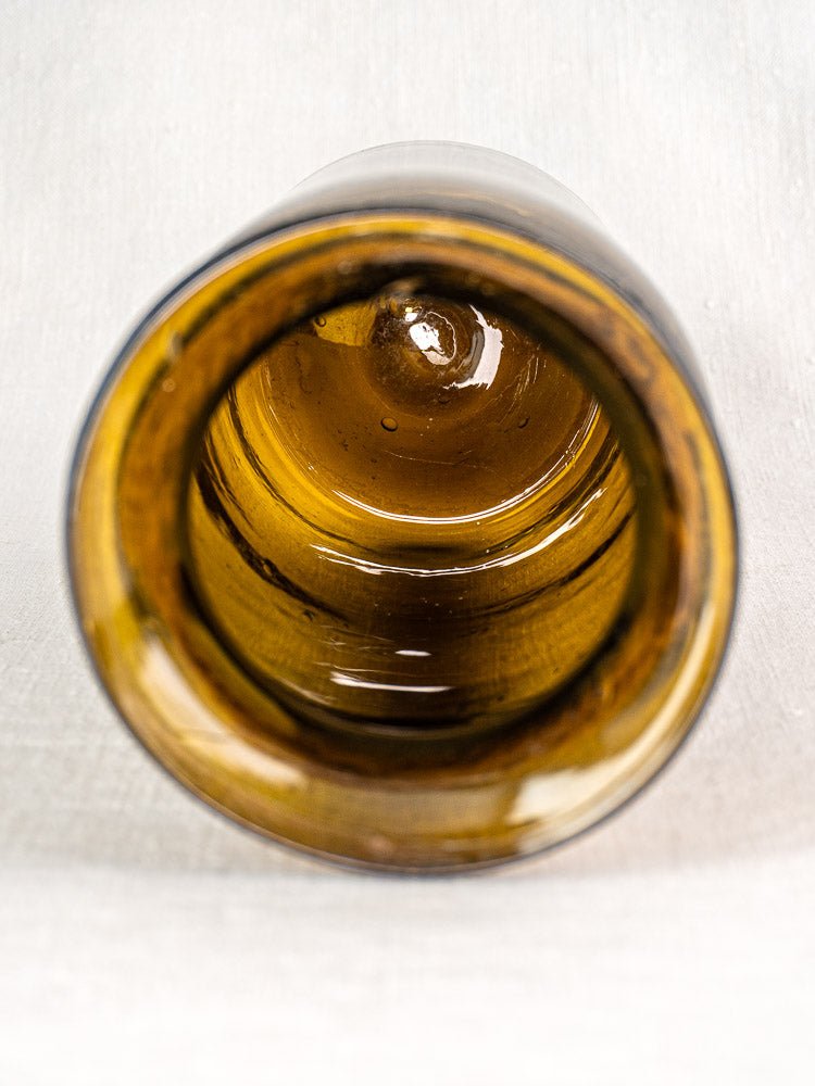 Antique French hand blown olive green glass bocal, late 19th century, side view on light textured surface.