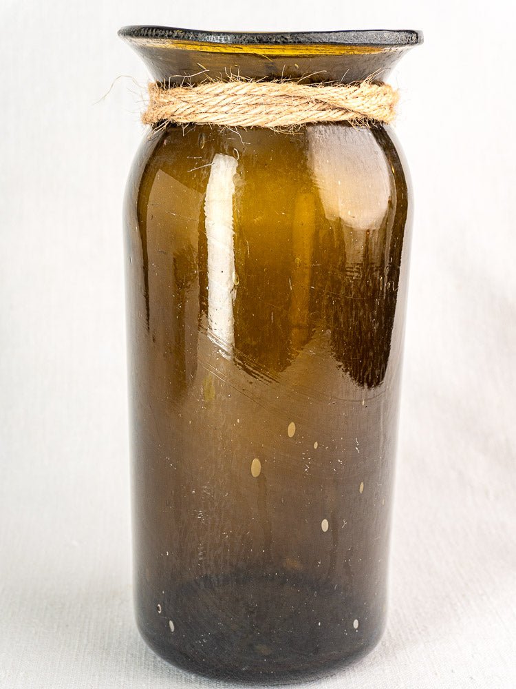 Antique French olive green hand-blown glass bocal with wide rim and twine bow, plain background.
