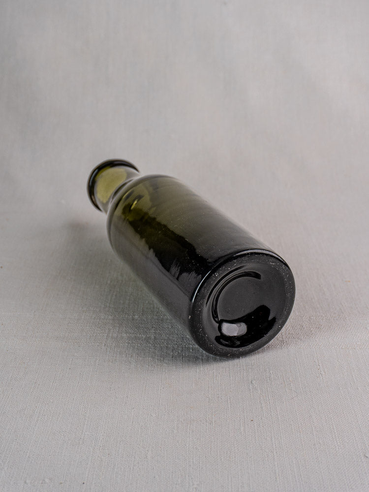 Antique French truffle jar, 18th–19th century, olive green hand-blown glass on gray surface.
