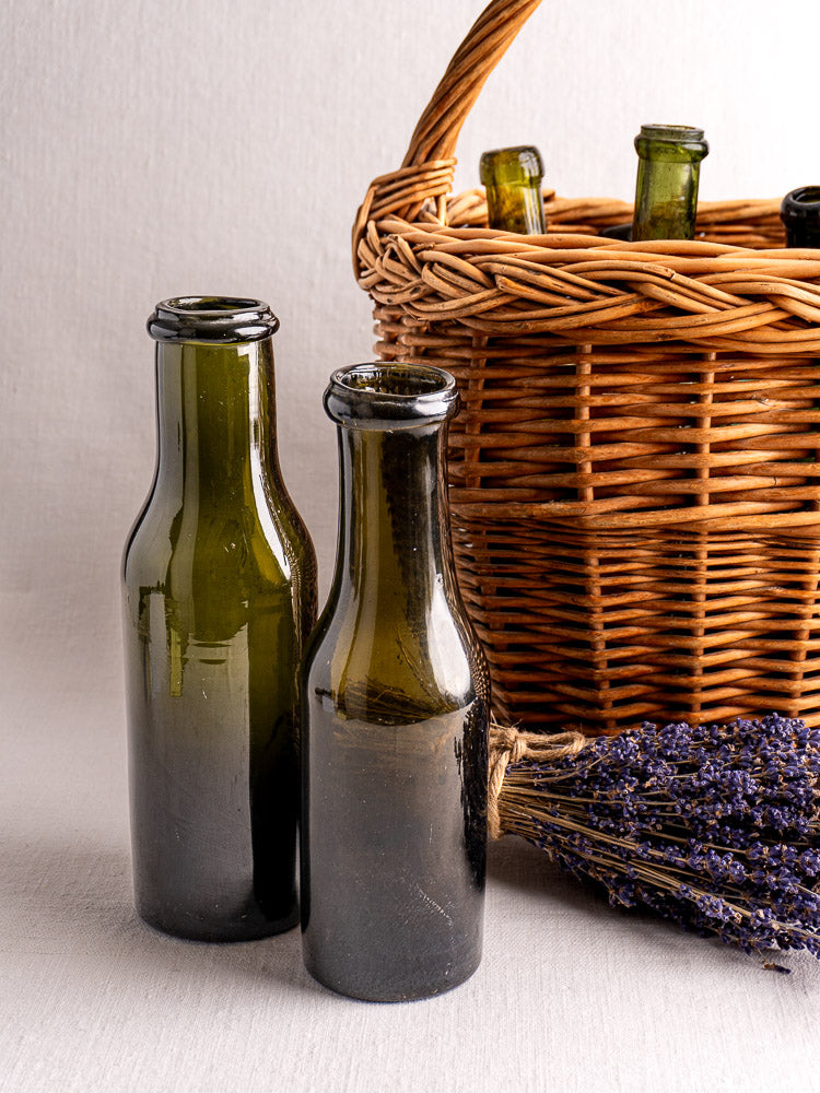 Antique French olive green glass truffle jars with wicker basket and dried lavender nearby.