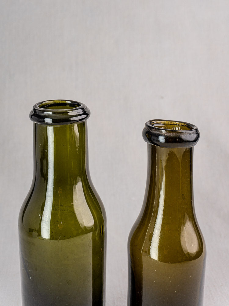 Pair of antique French truffle jars in olive green hand-blown glass, on gray background.