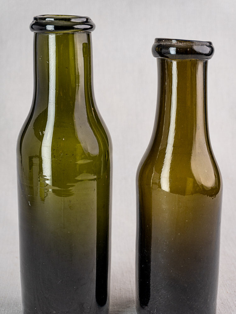 Pair of antique French truffle jars in olive green hand-blown glass on light surface.