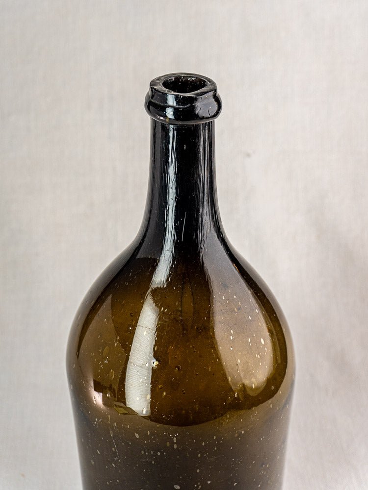 Large antique French hand blown wine bottle with narrow neck, dark olive glass, speckled finish.