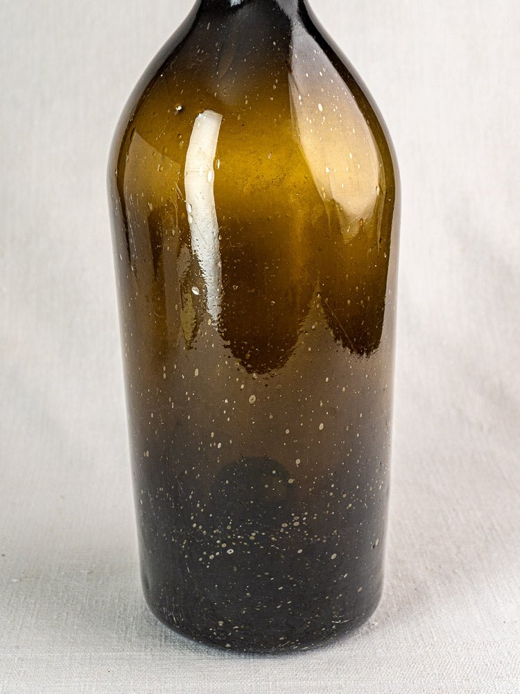 Large antique French hand blown wine bottle in dark olive glass with bubbles and imperfections.
