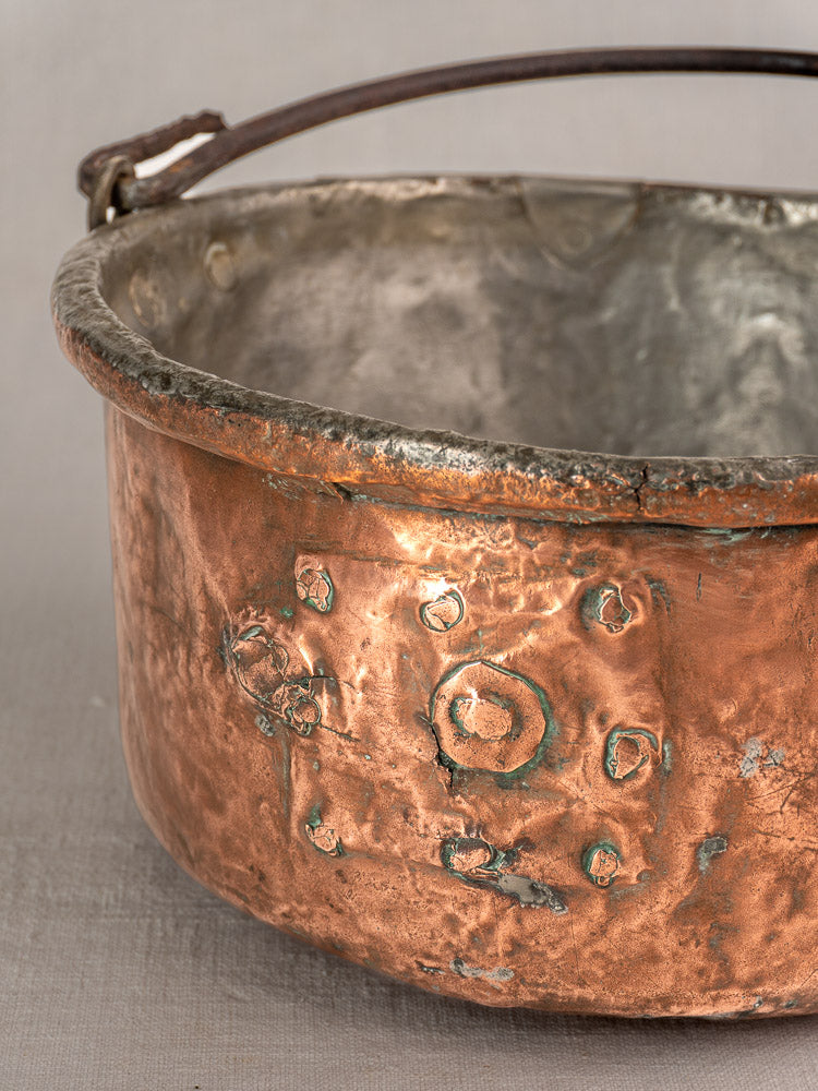 Antique French copper cauldron with patina, repairs, dents, and engraving marks reflecting rustic farmhouse style.