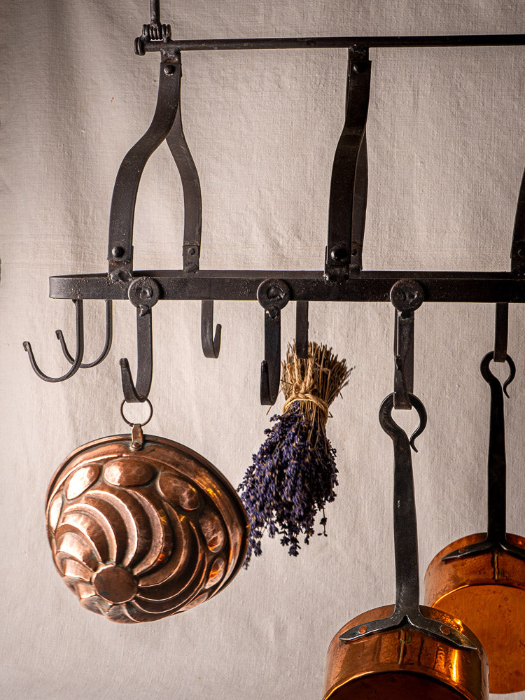 Antique French wrought iron hanging pot rack with hooks, copper mold, lavender, and copper pots.