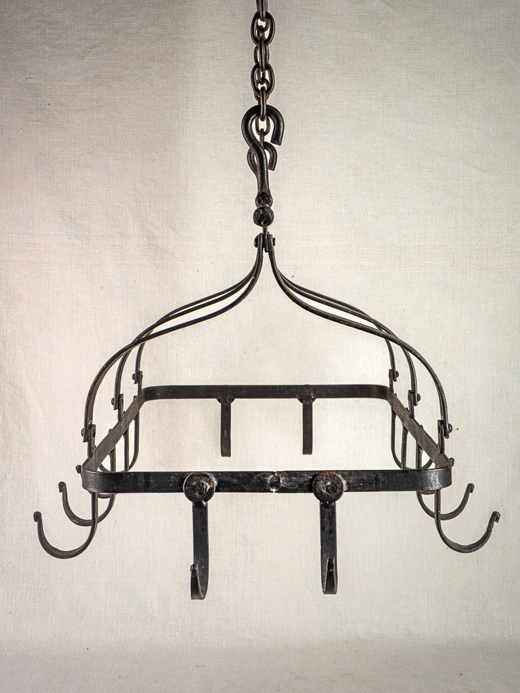 Antique French wrought iron hanging pot rack with square frame, multiple hooks, and curved supports.