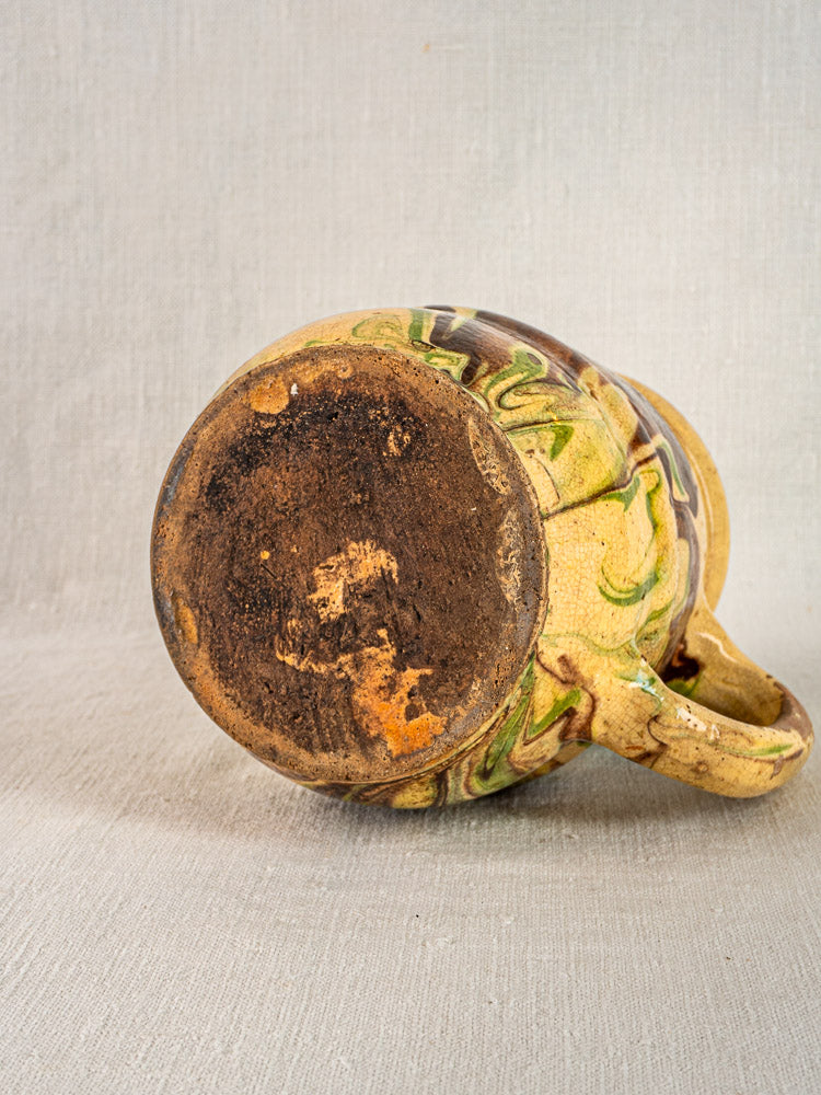 Antique French Savoie jaspé pitcher with yellow, green, and brown marbled glaze, textured base exposed.