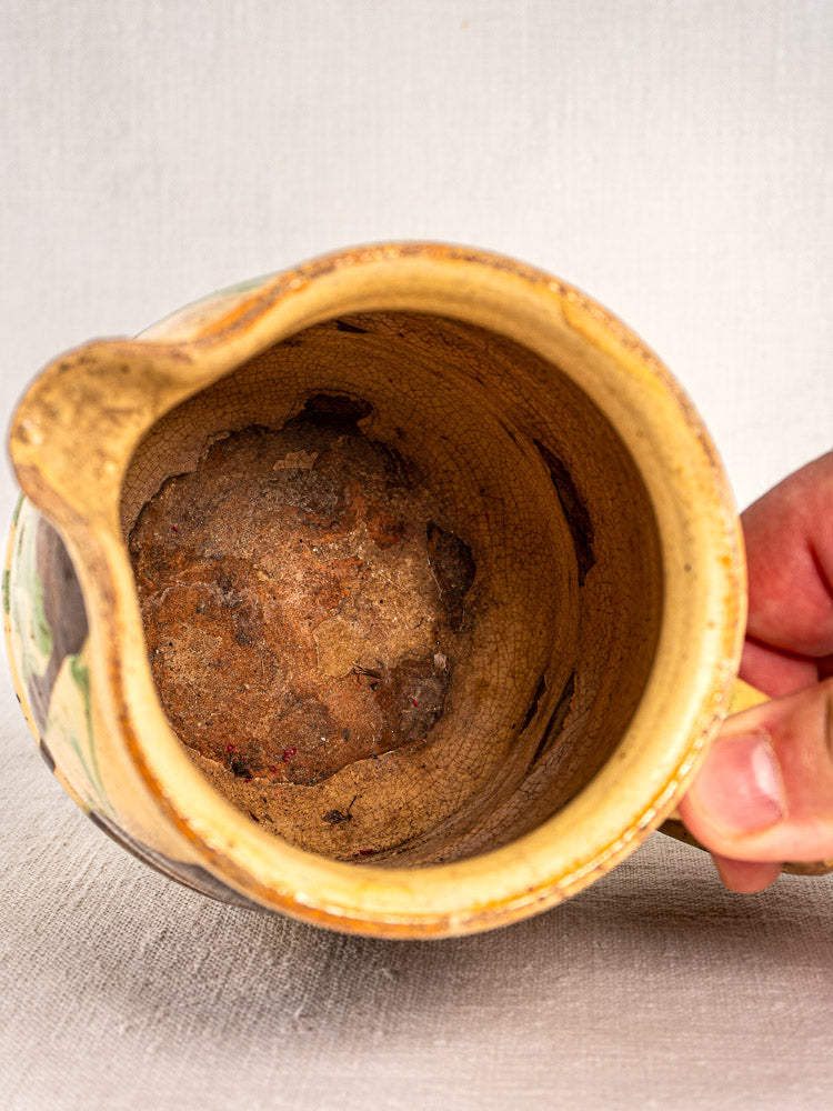 Antique French Savoie Jaspé pitcher with marbled glaze and worn interior showing brown residue.