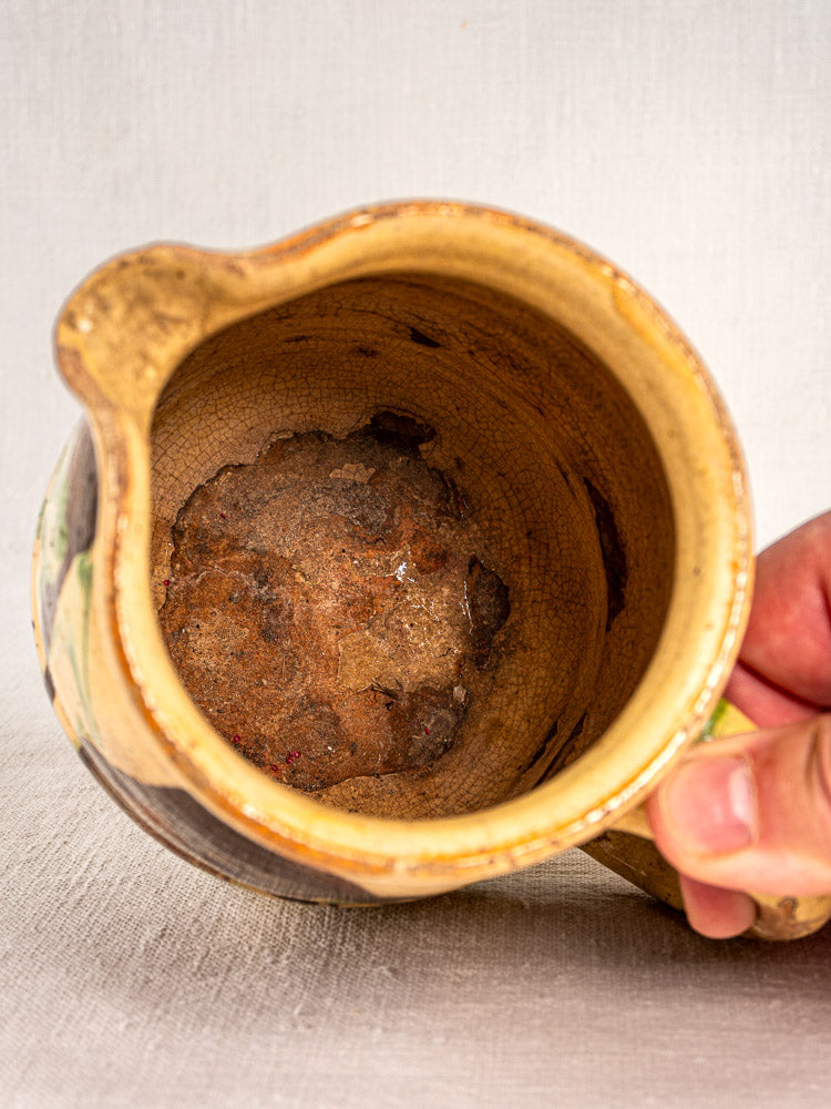 Antique French Jaspé pitcher with marbled glaze, visible chips, cracks, and rust stains.
