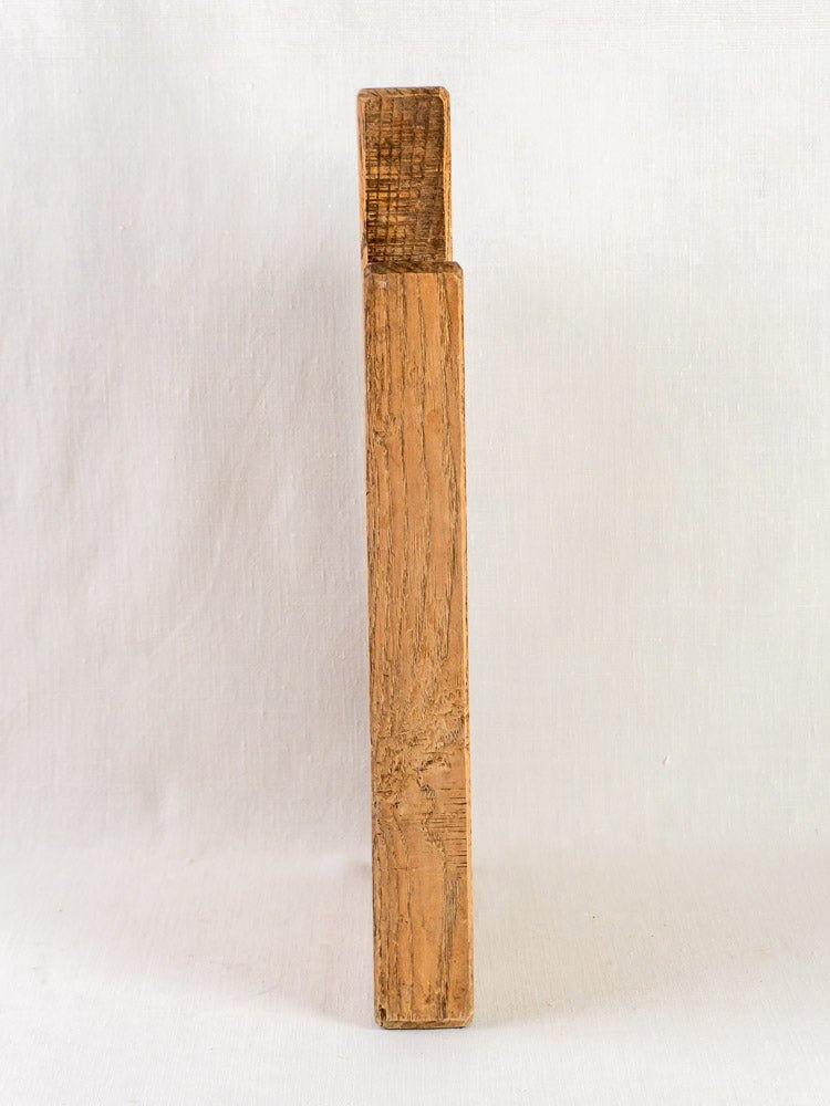 Late 19th-century antique French oak chopping board with rough grain and small top notch on white background.