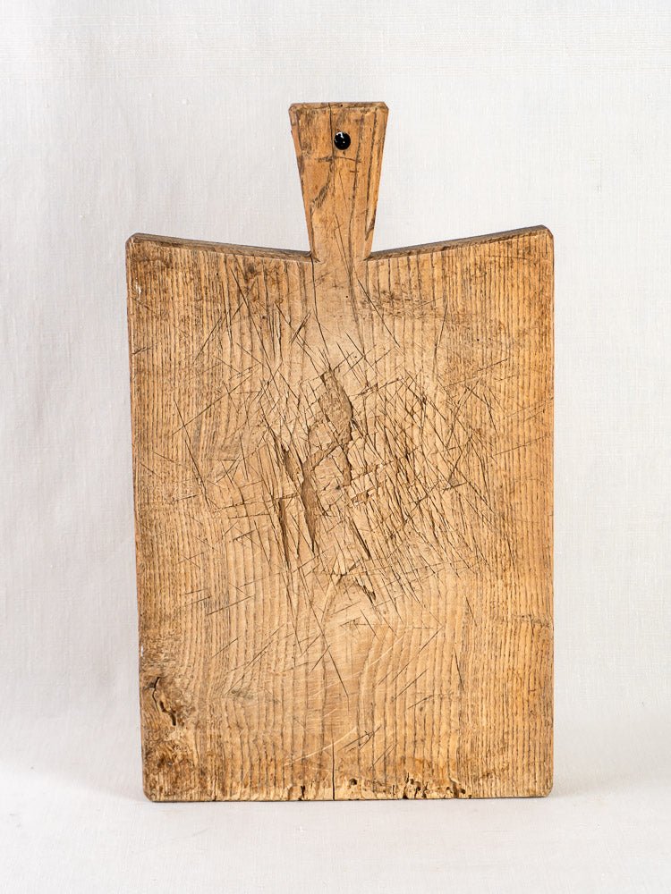 Antique French oak chopping board, late 19th century, rectangular with handle, knife marks visible, upright on light background.