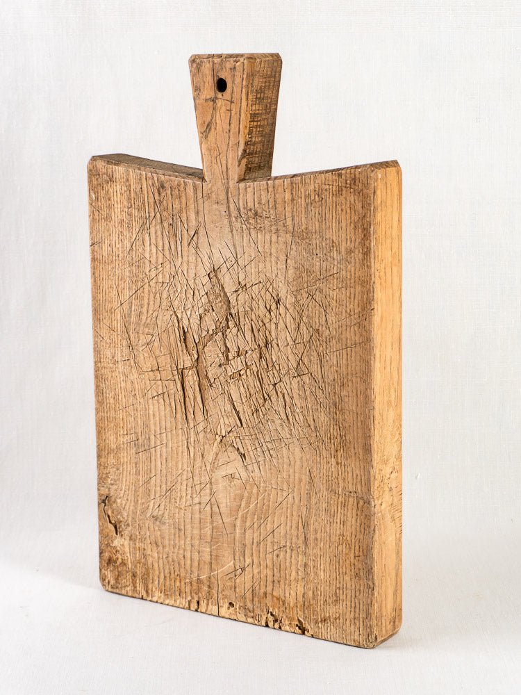Antique French oak chopping board, late 19th century, square with handle and aged knife marks.