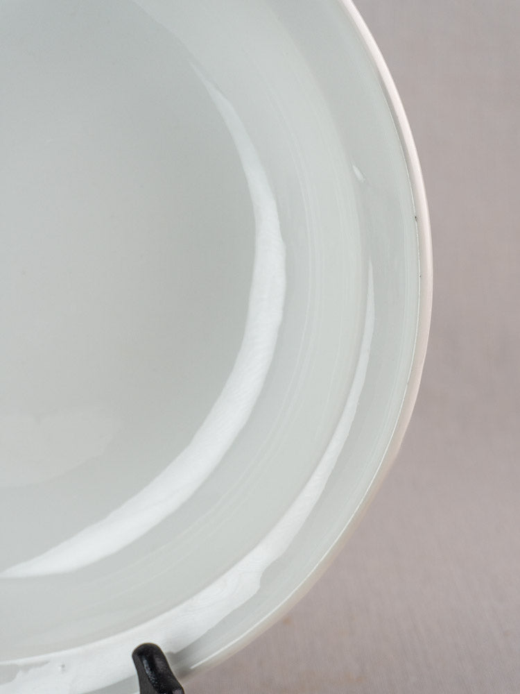 Antique French Frugier Limoges aluminite bowl with glossy white finish and curved rim; small black object at edge.