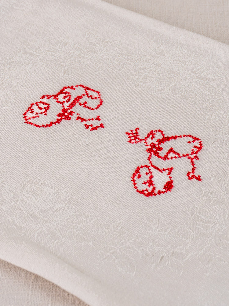 Antique French damask linen napkin with red monogram "P.G." and woven floral pattern.