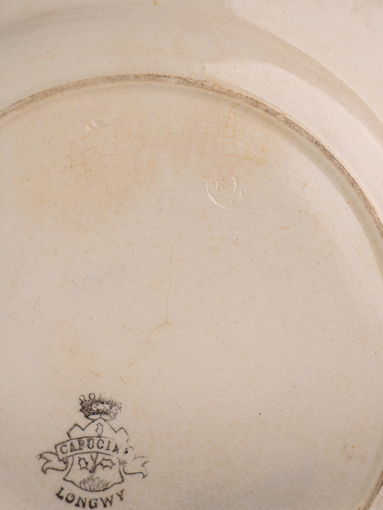 Underside of antique French faience plate, crackled glaze, CABUCHA LONGWY crest, Longwy Capucia impressed mark visible.