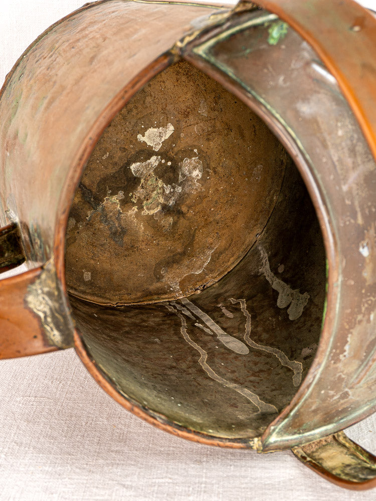Antique French copper hand-hammered watering can with rich patina and weathered interior on fabric.