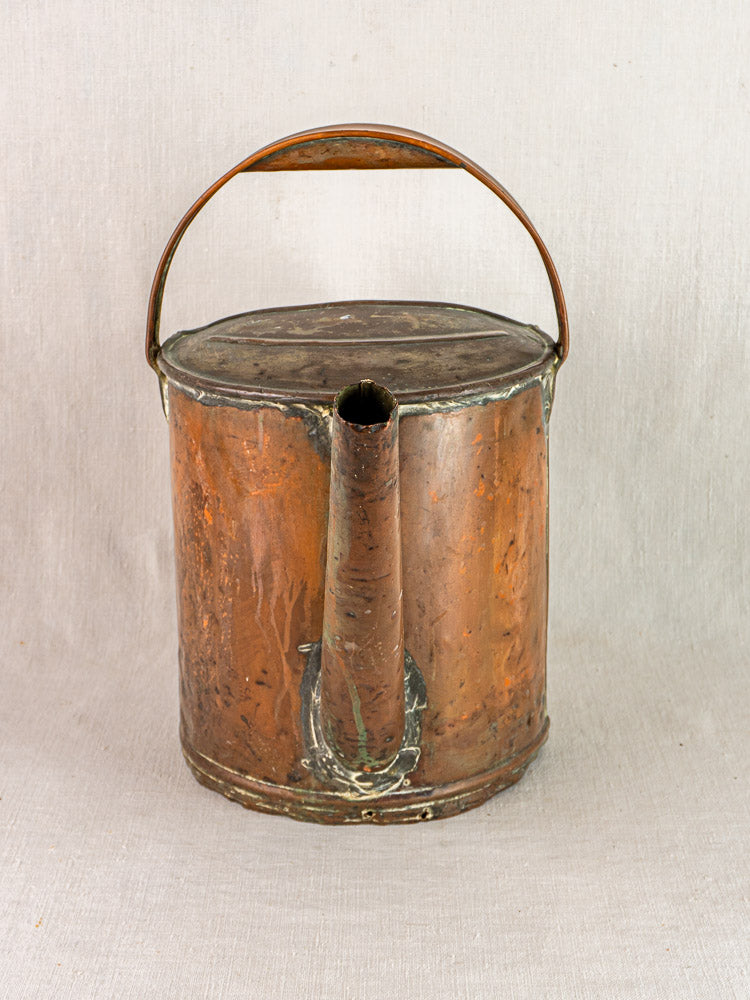 Antique French hand-hammered copper watering can with tall spout and curved handle, aged patina.
