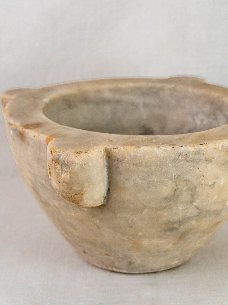French antique hand-carved marble mortar and pestle with rustic round shape, plain light background.
