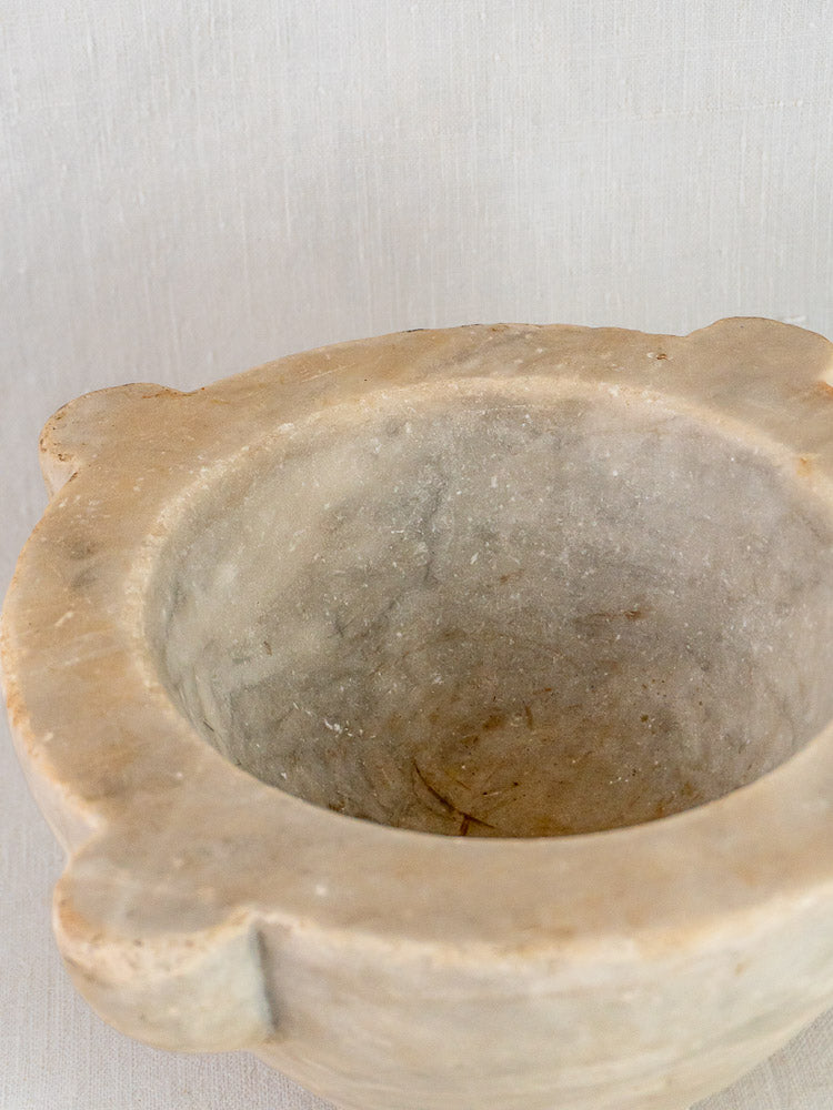 Antique French hand-carved marble mortar and pestle with three handles on a light background.