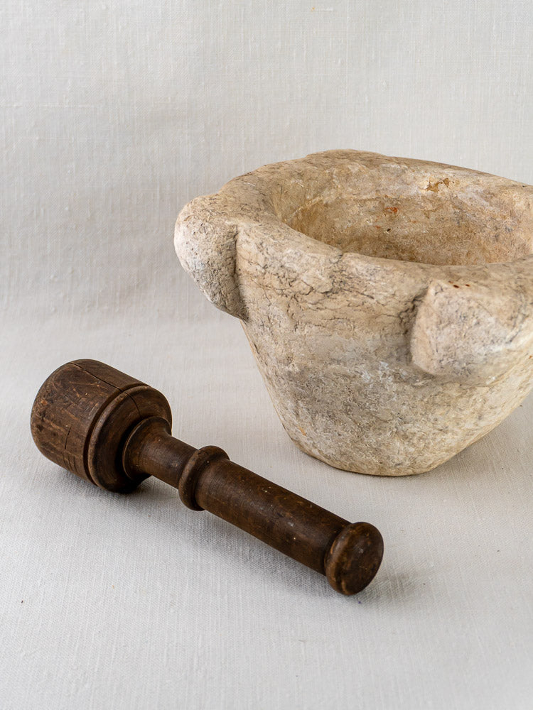 Hand-carved marble mortar and pestle from Antique French Stone Mortier collection on light fabric surface.