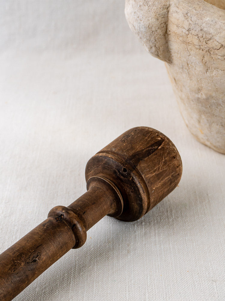 Hand-carved marble antique French mortar and pestle on a textured white surface.