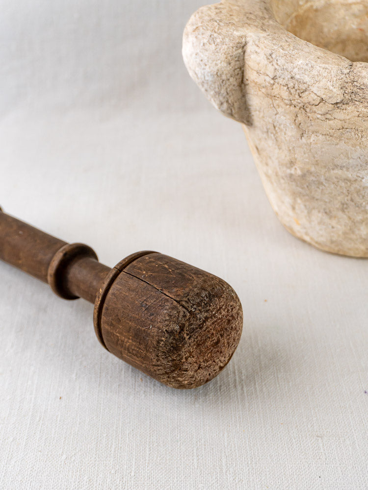 Hand-carved marble antique French mortar and pestle with rustic detailing on light fabric.