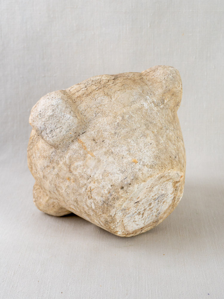 Antique French hand-carved marble mortar and pestle resting sideways on a light textured surface.