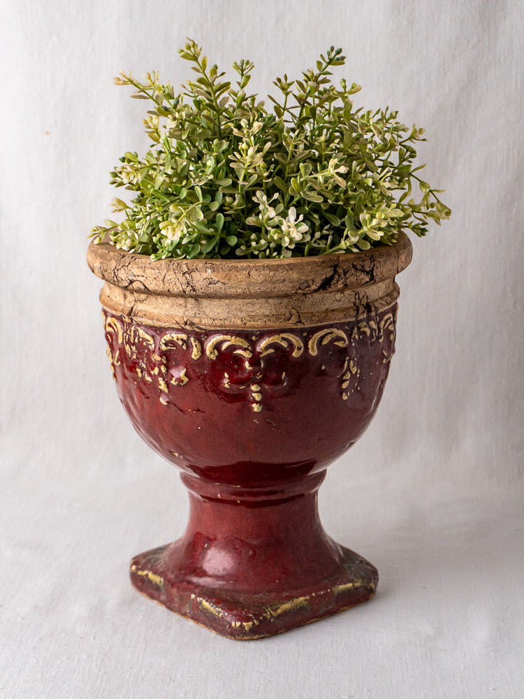 Oxblood French Terracotta Urn, ornate red and gold glazed cache-pot with plant, white background.