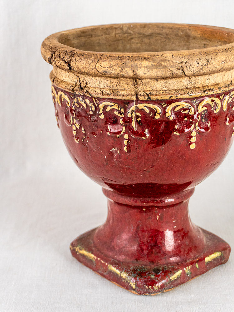 Antique French terracotta urn with wide rim, yellow and white trim, square pedestal base on white background.