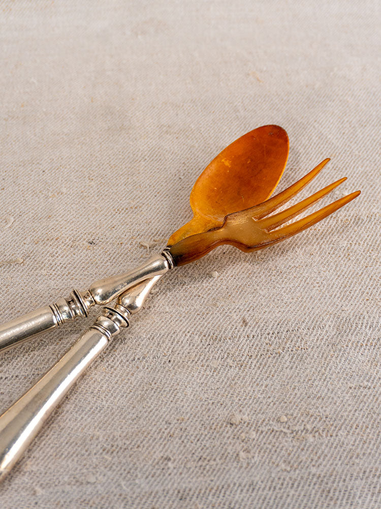 Antique French horn and silver plate salad servers, late 19th century, crossed on beige fabric.