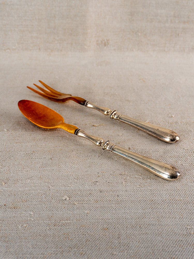 Antique French horn and silver plate salad servers, late 19th century, on beige textured fabric.