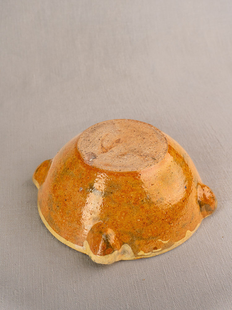 Antique French yellow glazed Provençal aïoli mortar, late 19th century, showing rounded feet on gray surface.