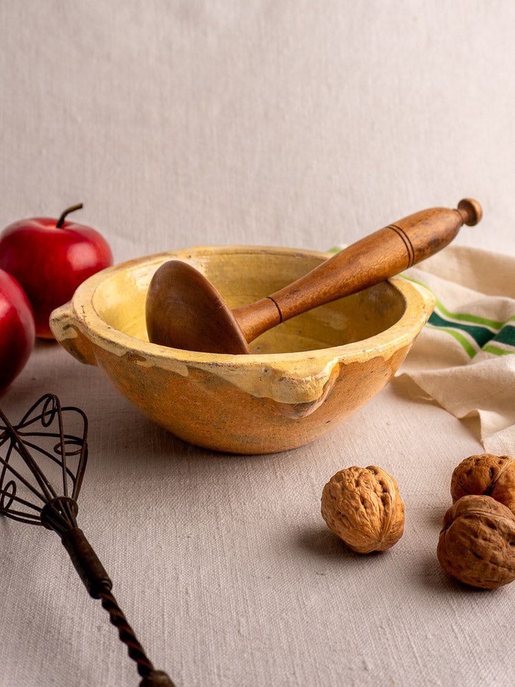 French yellow glazed Provençal mortar and wooden pestle, late 19th century, with apples, walnuts, whisk, striped cloth.