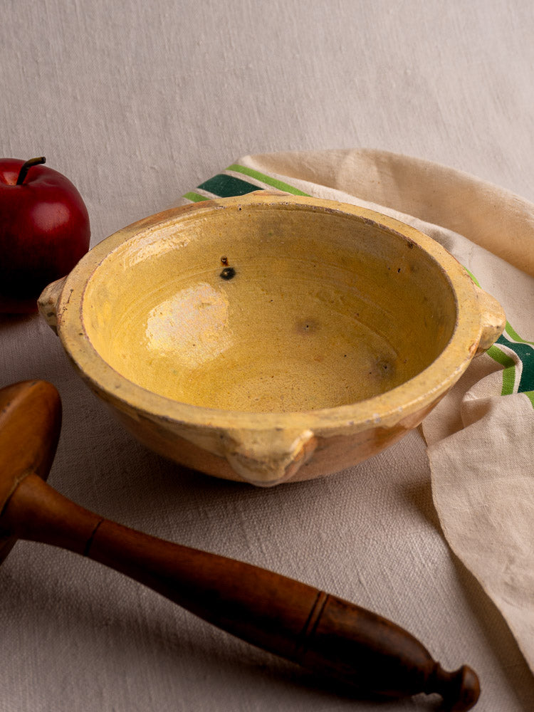 Late 19th-century French yellow glazed mortar and pestle on cloth with apple and linen towel.